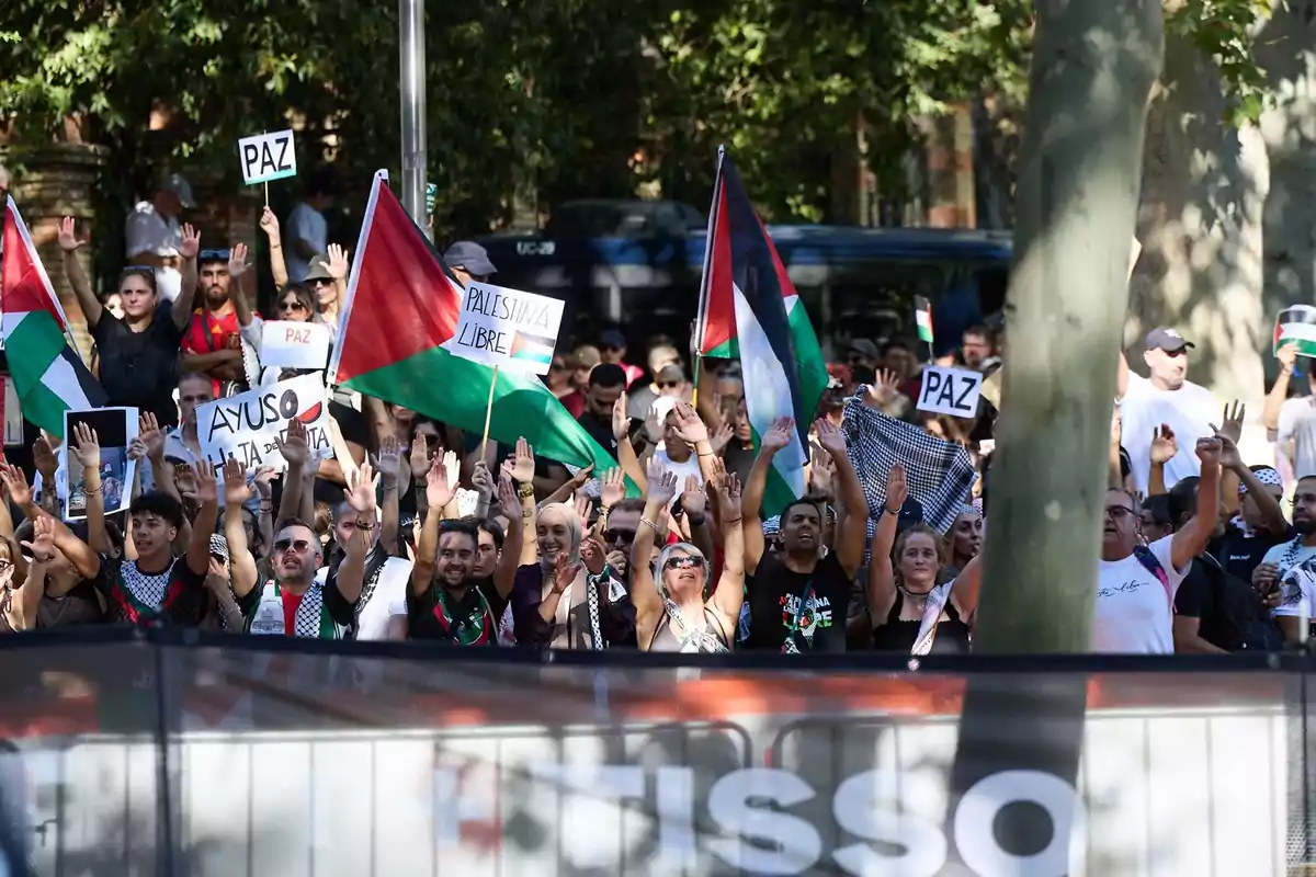 Manifestación con personas levantando las manos, ondeando banderas palestinas y sosteniendo carteles que piden paz y libertad para Palestina Manifestación con personas levantando las manos, ondeando banderas palestinas y sosteniendo carteles que piden paz y libertad para Palestina