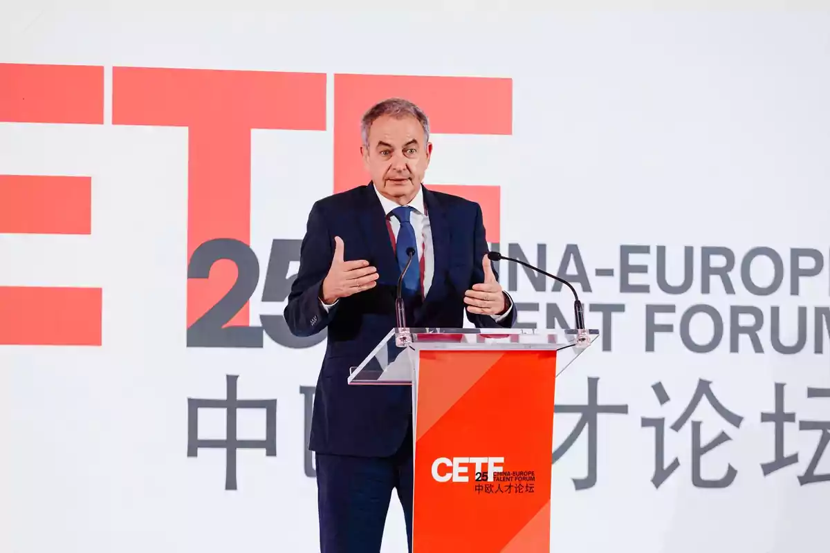 Hombre de traje hablando en un podio durante un foro titulado China-Europe Talent Forum con letras grandes en el fondo Hombre de traje hablando en un podio durante un foro titulado China-Europe Talent Forum con letras grandes en el fondo