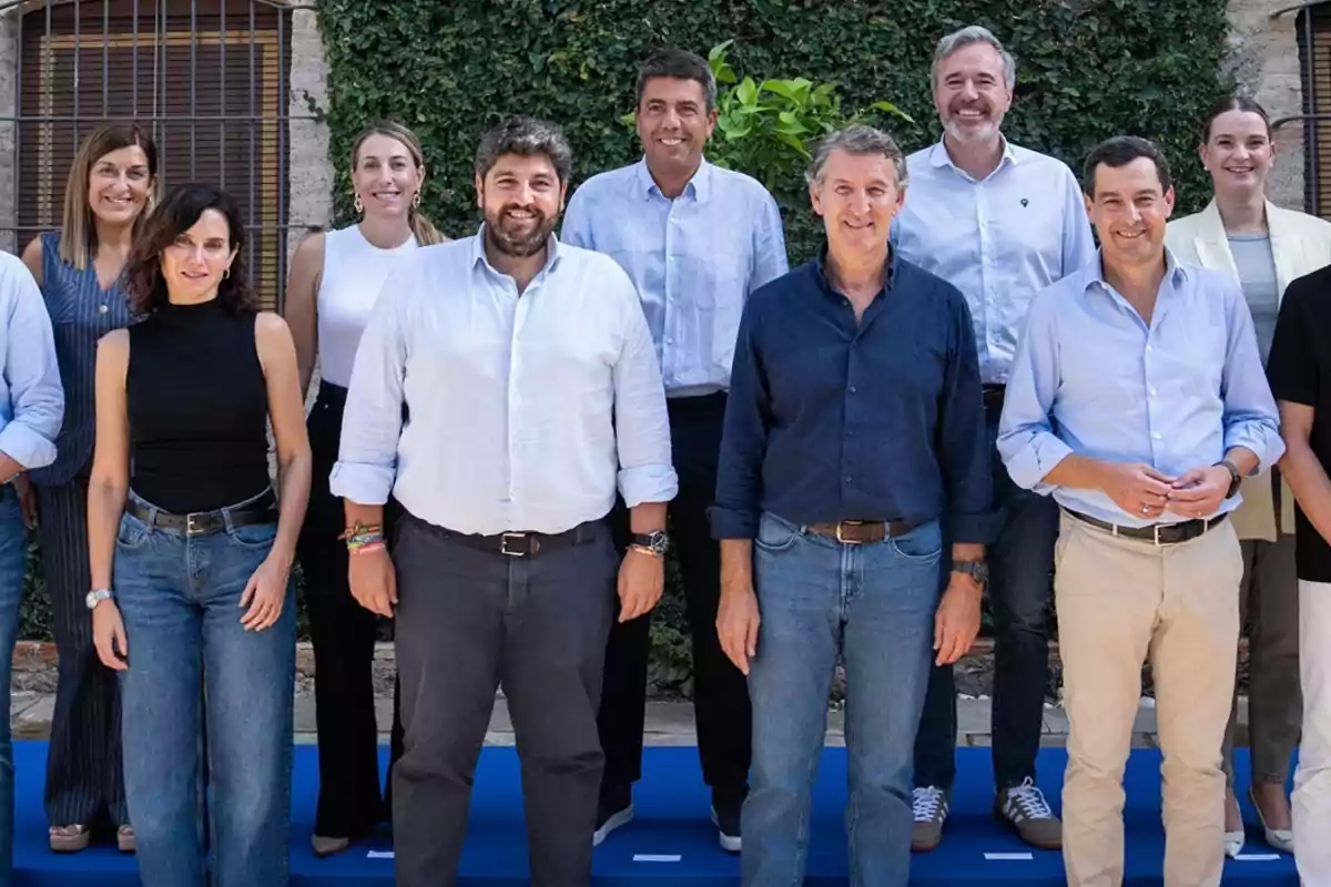 Grupo de personas posando juntas al aire libre frente a una pared cubierta de plantas Grupo de personas posando juntas al aire libre frente a una pared cubierta de plantas