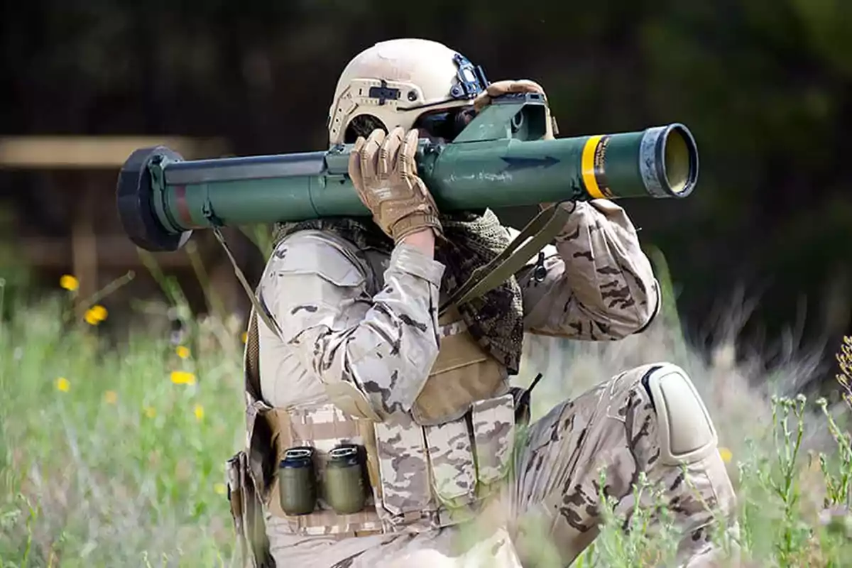 Soldado con uniforme de camuflaje y casco usando un lanzacohetes portátil en un entorno natural