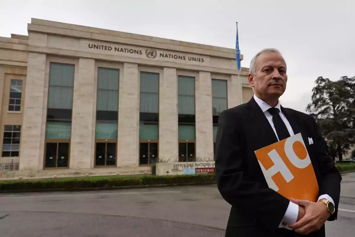 Hombre de traje sosteniendo una carpeta naranja frente a un edificio de la ONU Hombre de traje sosteniendo una carpeta naranja frente a un edificio de la ONU
