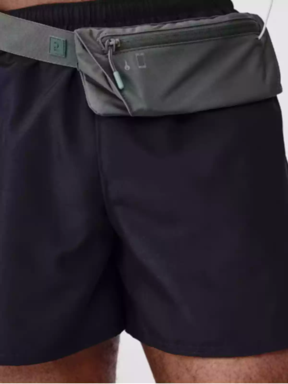 Persona usando una riñonera gris sobre pantalones oscuros Persona usando una riñonera gris sobre pantalones oscuros