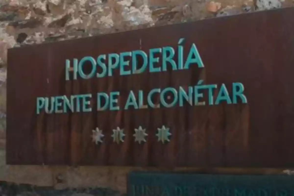 Letrero de la Hospedería Puente de Alconétar sobre una pared de piedra