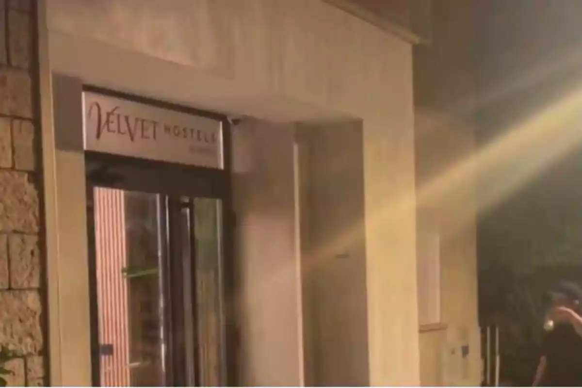 Entrada de un hostal llamado Velvet Hostels iluminada de noche