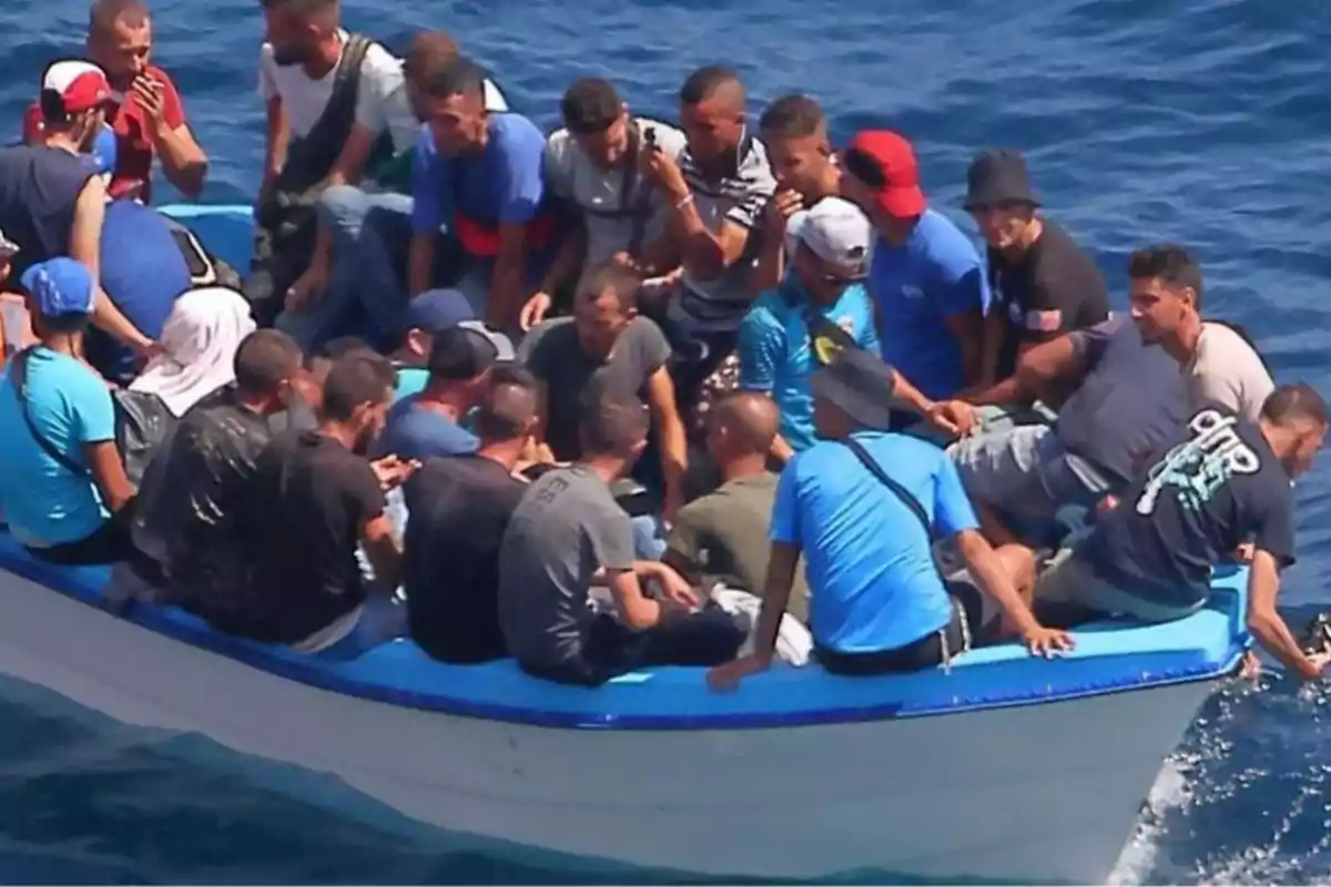 Un grupo de personas viaja en una pequeña embarcación sobre el mar, la mayoría están sentadas y parecen estar muy juntas Un grupo de personas viaja en una pequeña embarcación sobre el mar, la mayoría están sentadas y parecen estar muy juntas