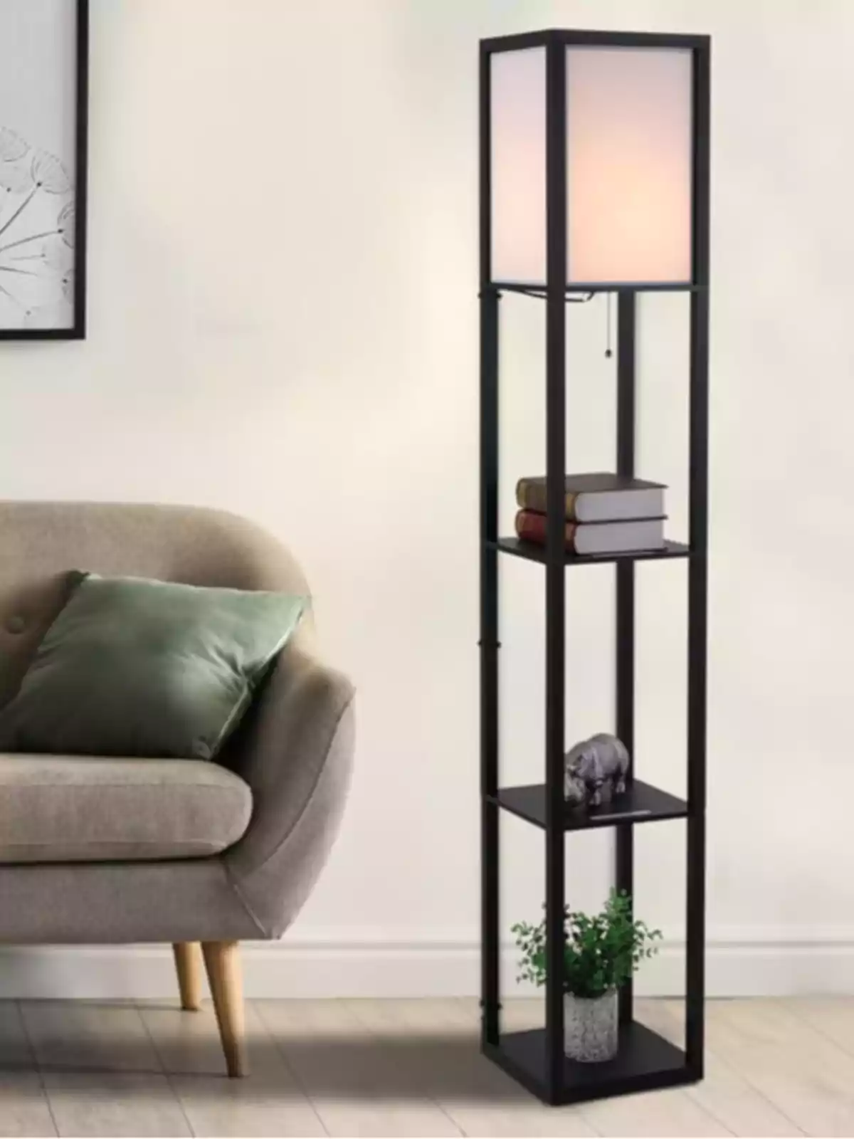 Lámpara de pie moderna con estructura negra y estantes, decorada con libros, una figura de rinoceronte y una planta, junto a un sofá beige con cojín verde en una sala de estar.