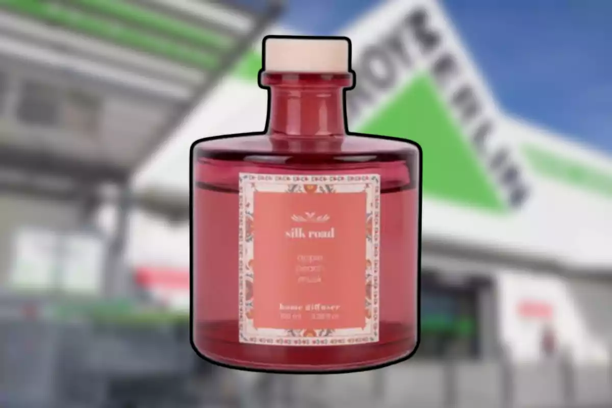 Frasco difusor de aroma color rosa con etiqueta decorativa al frente de una tienda Leroy Merlin desenfocada.