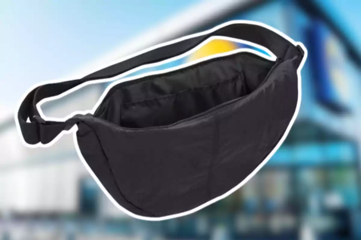 Bolsa tipo cangurera negra con correa ajustable sobre un fondo desenfocado de una tienda