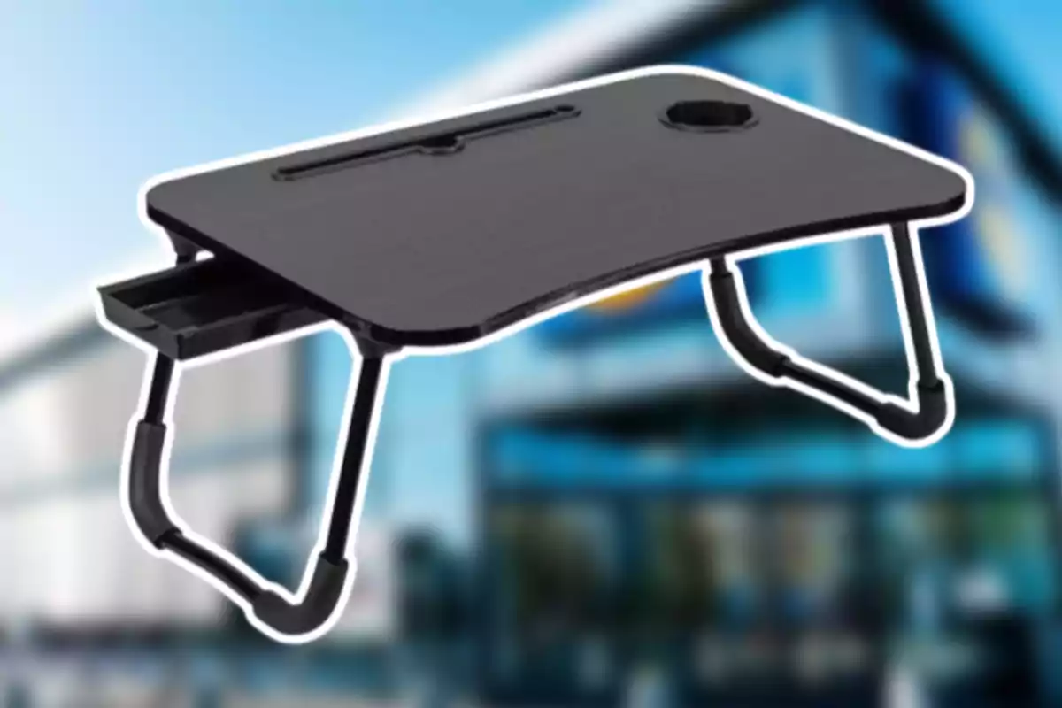 Mesa portátil negra con patas plegables y un cajón lateral sobre un fondo desenfocado de edificio moderno Mesa portátil negra con patas plegables y un cajón lateral sobre un fondo desenfocado de edificio moderno