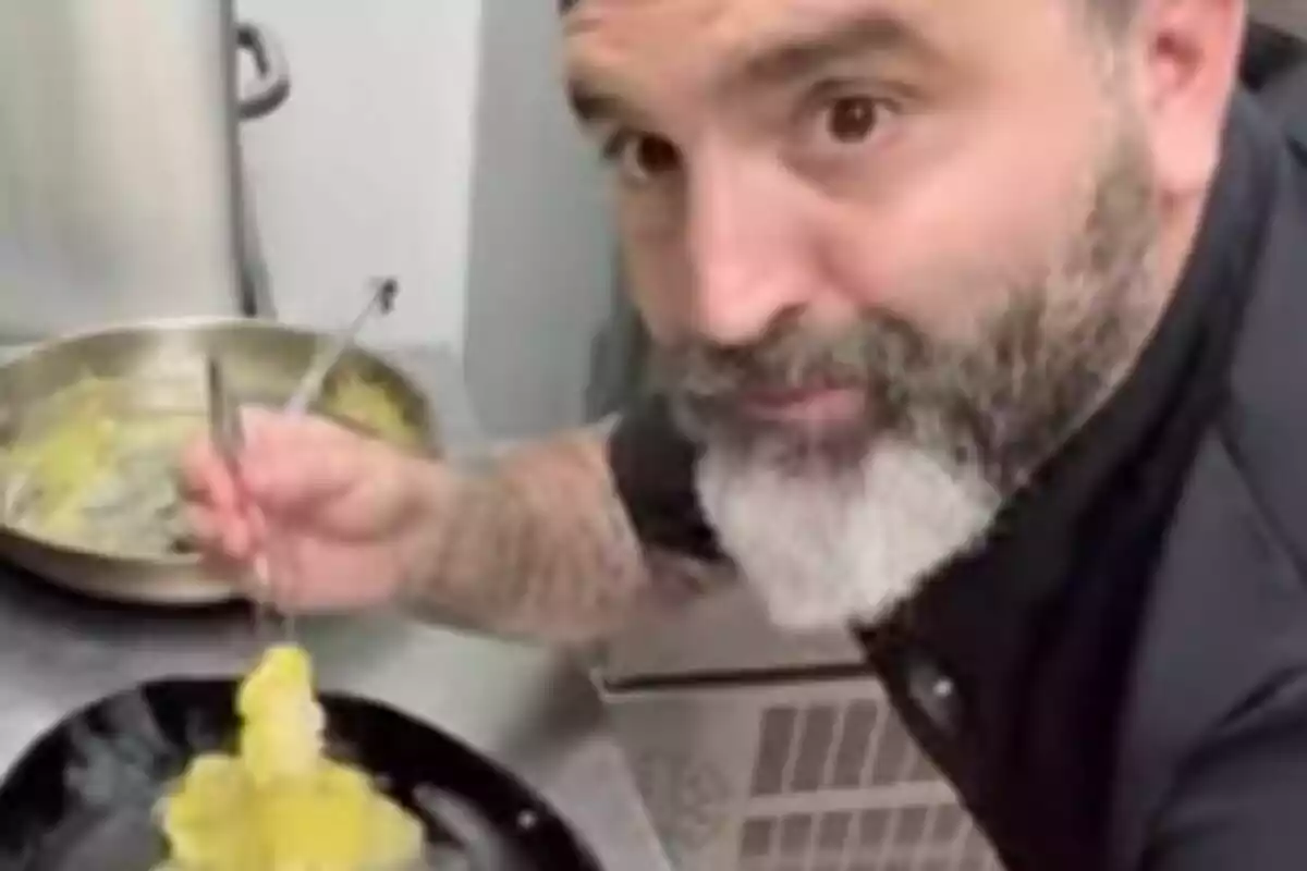Hombre con barba, que es Miguel Ángel Cadiz, cocinando en una cocina profesional mientras sostiene unas pinzas y un plato con comida. Hombre con barba, que es Miguel Ángel Cadiz, cocinando en una cocina profesional mientras sostiene unas pinzas y un plato con comida.