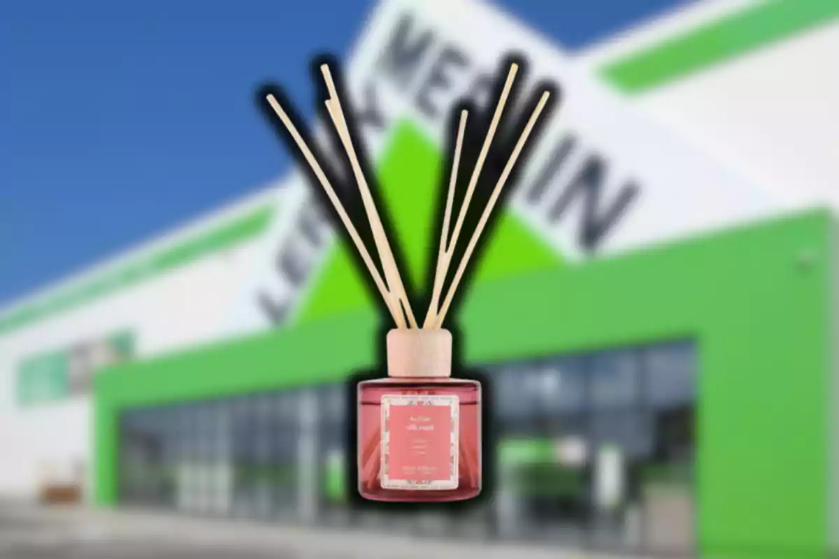 Difusor de varillas con líquido aromático en primer plano sobre un fondo desenfocado de una tienda con fachada verde y blanca Difusor de varillas con líquido aromático en primer plano sobre un fondo desenfocado de una tienda con fachada verde y blanca