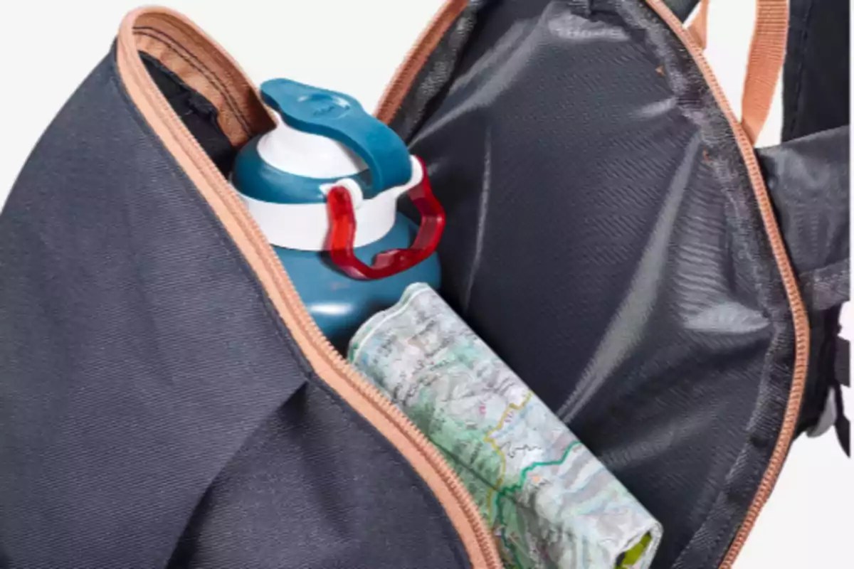 Mochila abierta que muestra una botella azul y un mapa en su interior Mochila abierta que muestra una botella azul y un mapa en su interior