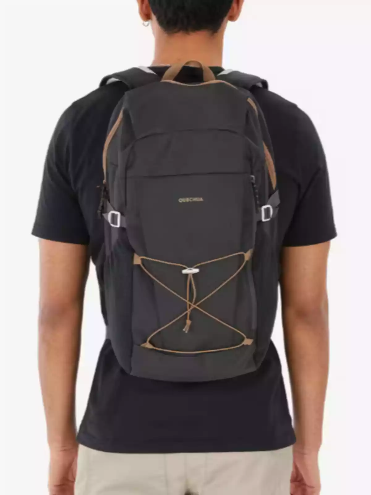 Persona de espaldas usando una mochila negra marca Quechua sobre una camiseta negra y pantalones beige Persona de espaldas usando una mochila negra marca Quechua sobre una camiseta negra y pantalones beige