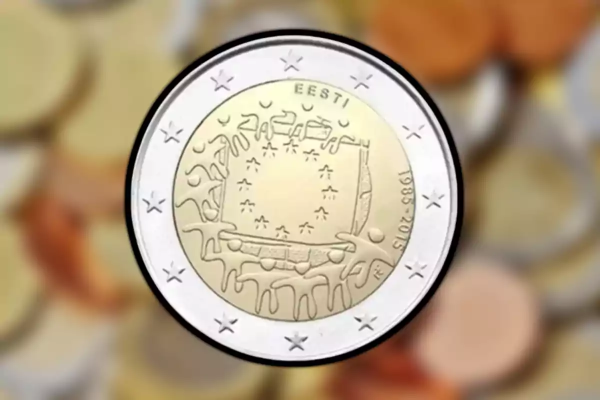 Moneda conmemorativa de Estonia con diseño artístico y estrellas en el borde sobre un fondo desenfocado de otras monedas