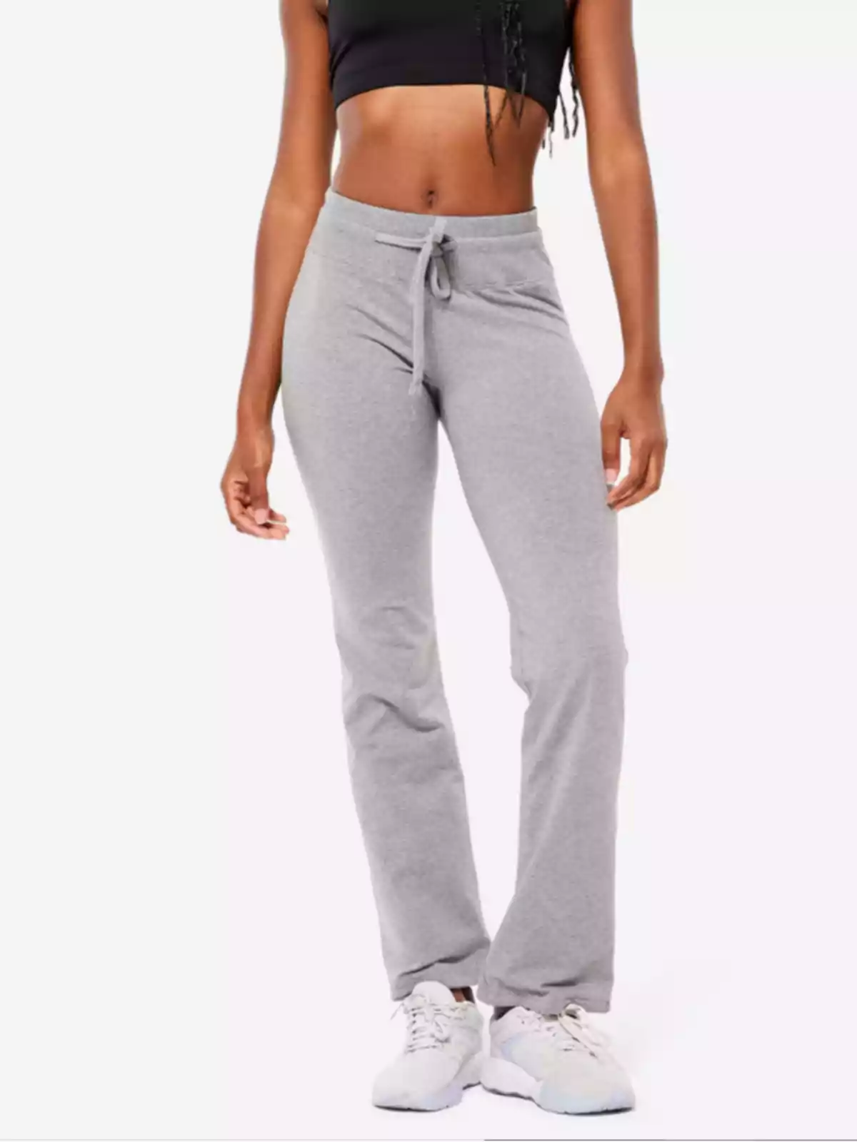 Mujer usando pantalones deportivos grises y top negro con tenis blancos Mujer usando pantalones deportivos grises y top negro con tenis blancos