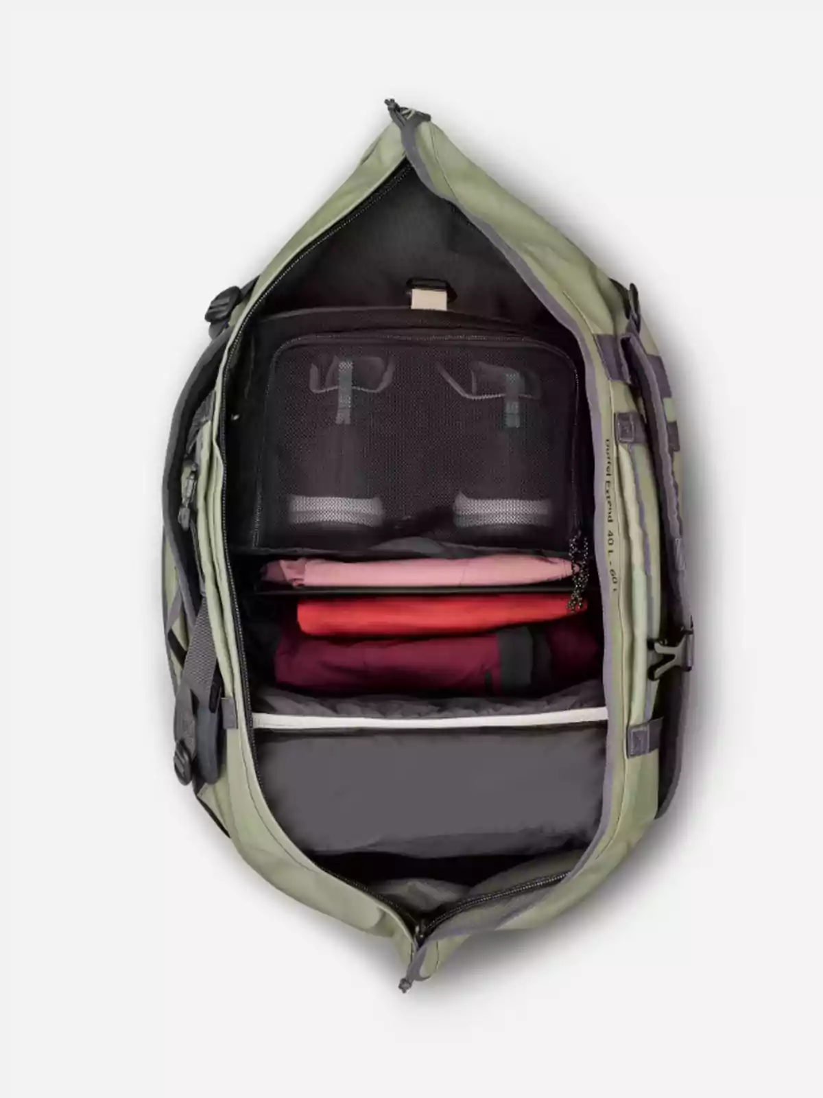 Mochila verde abierta vista desde arriba mostrando su interior organizado con ropa doblada y compartimentos de malla negra