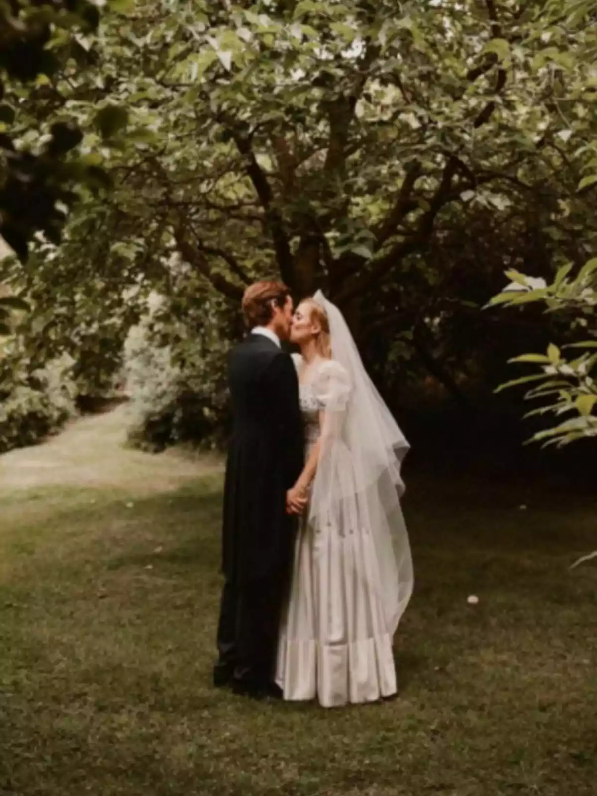 Edoardo Mapelli y Beatriz de York recién casados besándose en un jardín rodeado de árboles