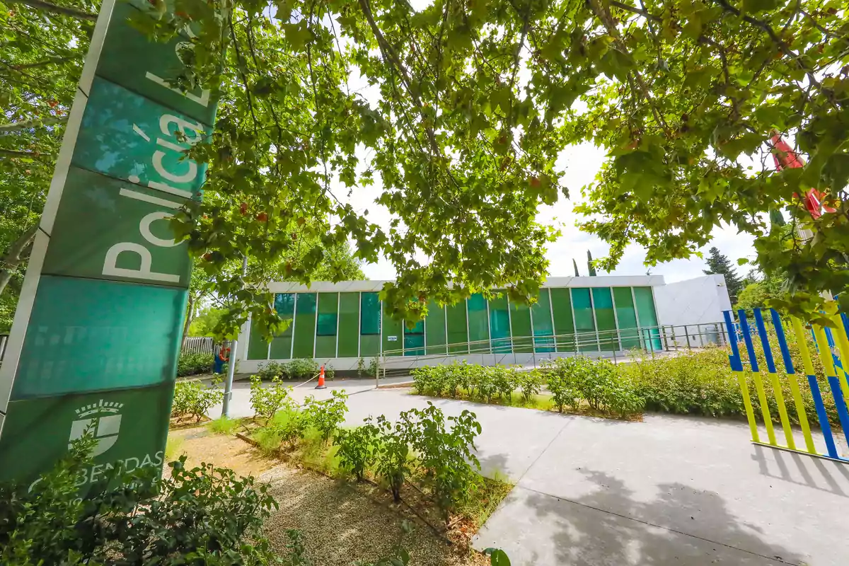 Edificio moderno de la policía local rodeado de árboles y vegetación en un día soleado
