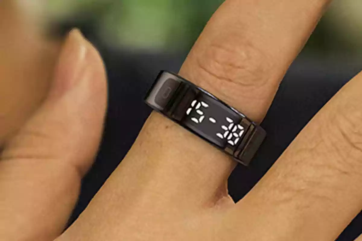 Persona usando un anillo inteligente negro con pantalla digital que muestra la hora en uno de sus dedos