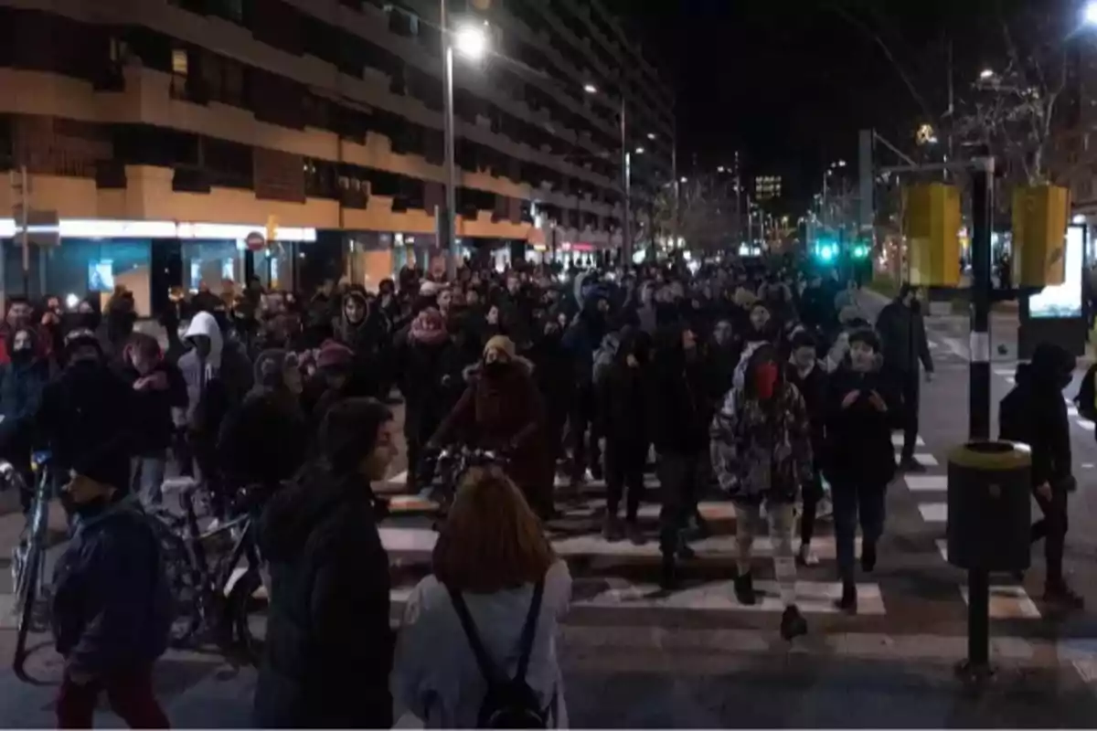 Una multitud de personas camina por una calle de la ciudad durante la noche