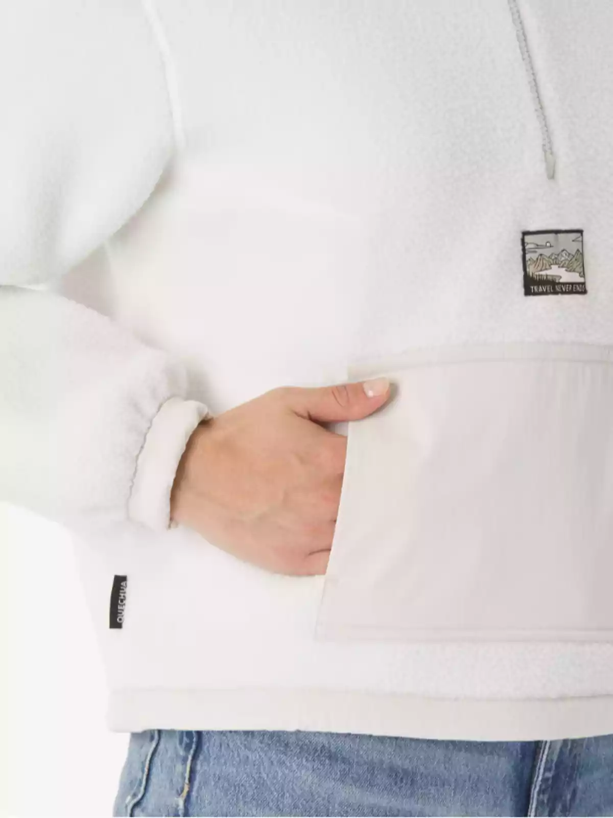 Persona con chaqueta blanca de forro polar y bolsillo frontal, usando jeans y metiendo una mano en el bolsillo