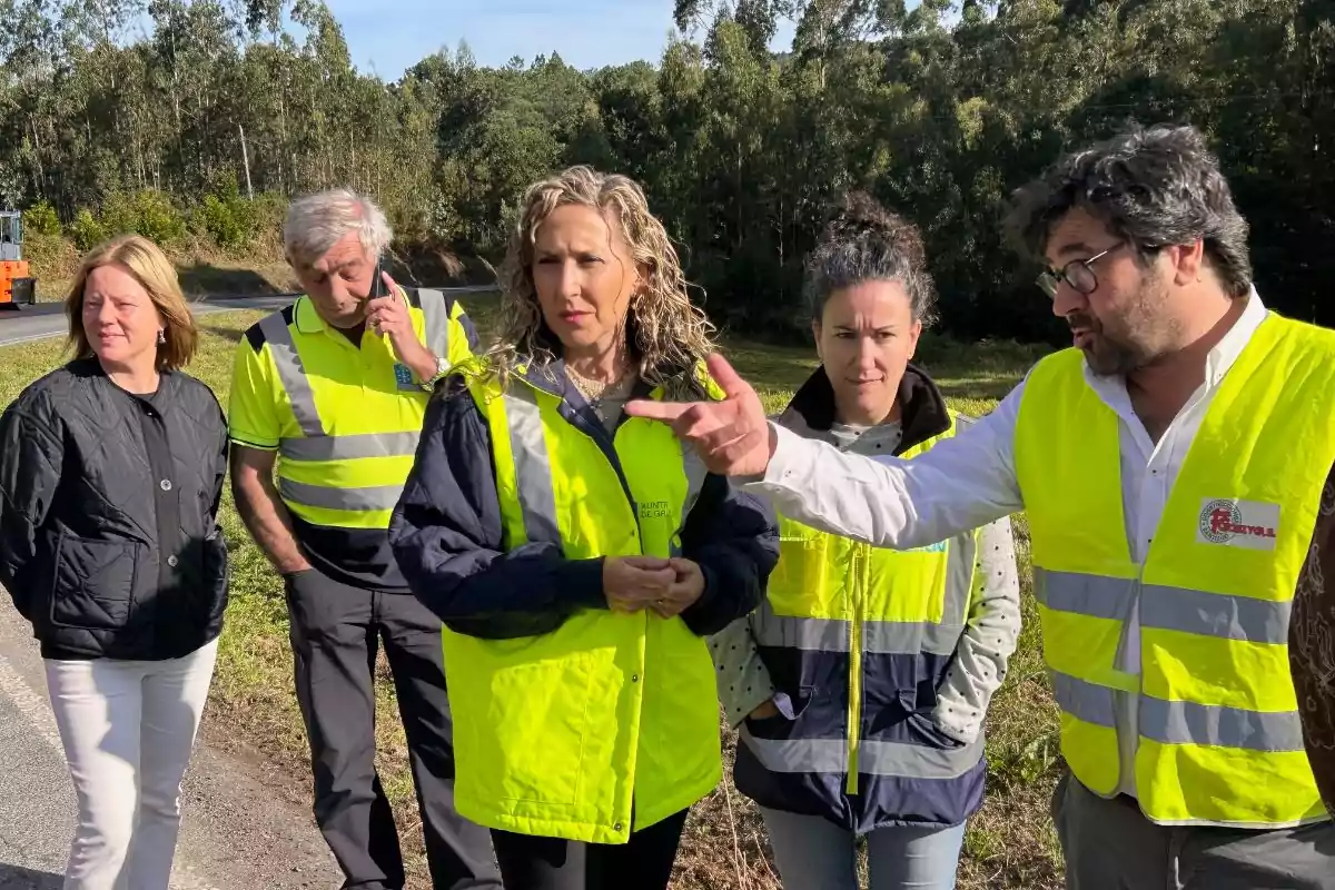 Cinco personas con chalecos reflectantes conversan al aire libre junto a una carretera rodeada de árboles Cinco personas con chalecos reflectantes conversan al aire libre junto a una carretera rodeada de árboles