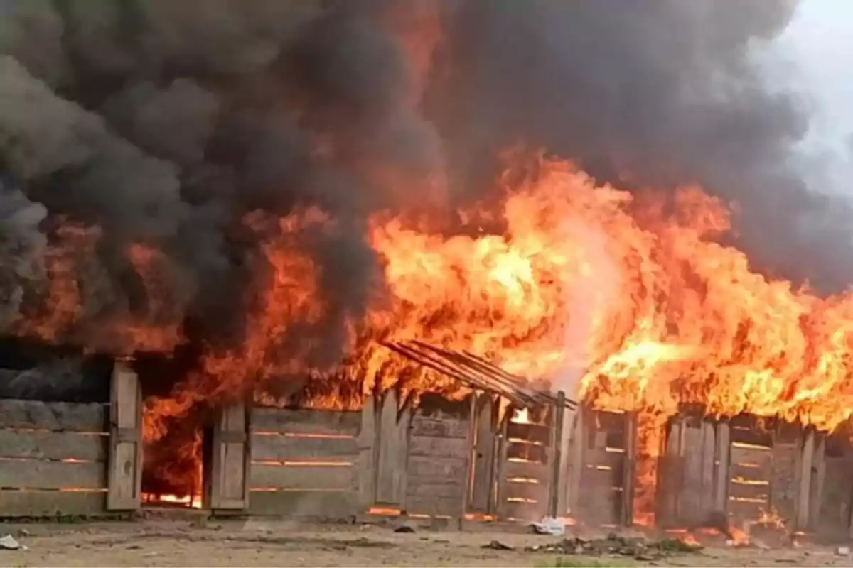 Incendio consumiendo una estructura de madera con grandes llamas y humo negro