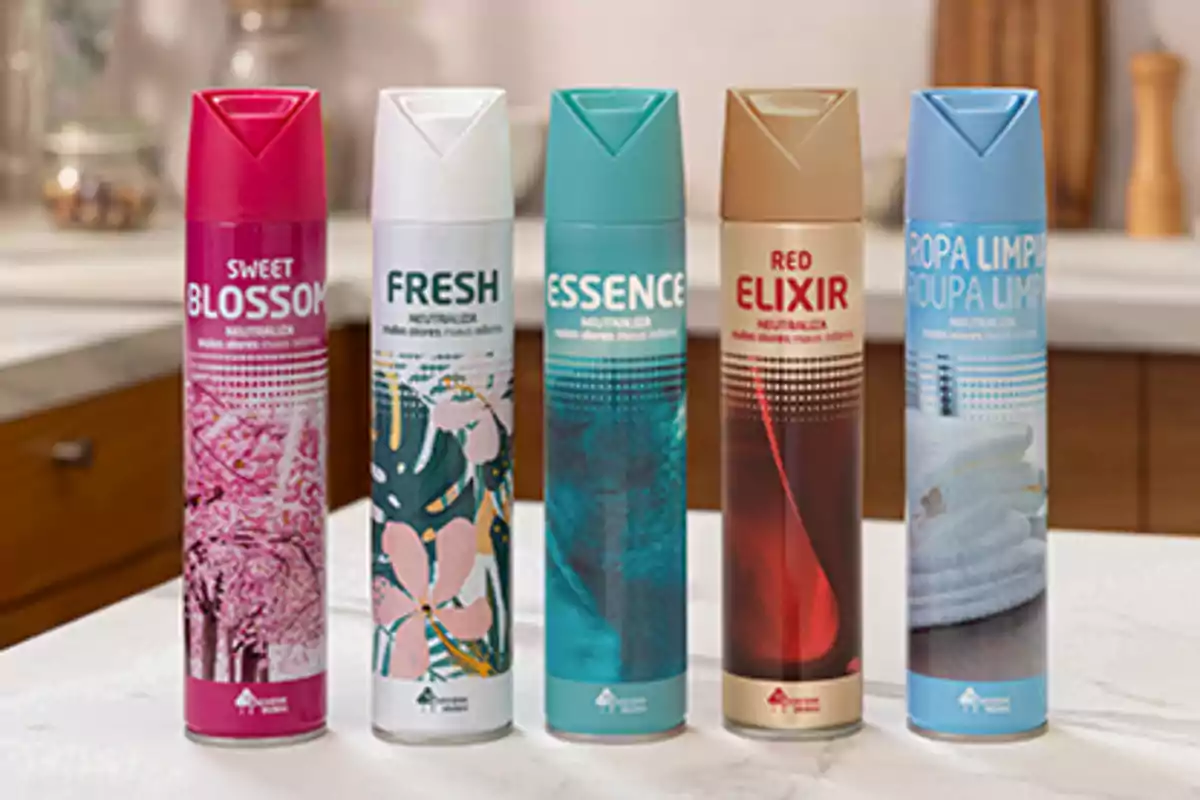 Cinco aerosoles aromatizantes de diferentes fragancias están alineados sobre una encimera de cocina Cinco aerosoles aromatizantes de diferentes fragancias están alineados sobre una encimera de cocina