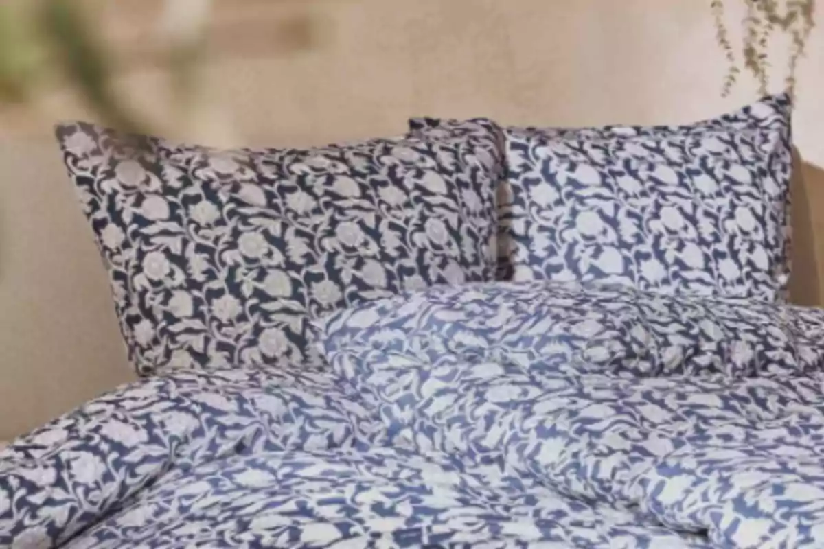 Cama con sábanas y almohadas de estampado floral en tonos azul y blanco
