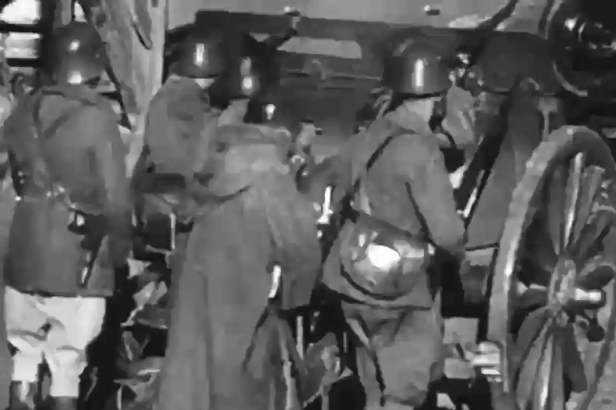 Soldados con cascos y abrigos operando una pieza de artillería antigua en blanco y negro