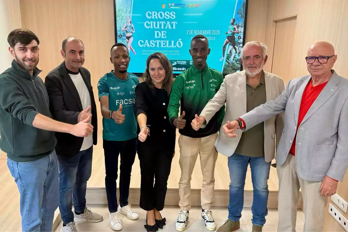 Siete personas posan sonrientes haciendo el gesto de pulgar arriba frente a un cartel promocional del Cross Ciutat de Castelló Siete personas posan sonrientes haciendo el gesto de pulgar arriba frente a un cartel promocional del Cross Ciutat de Castelló