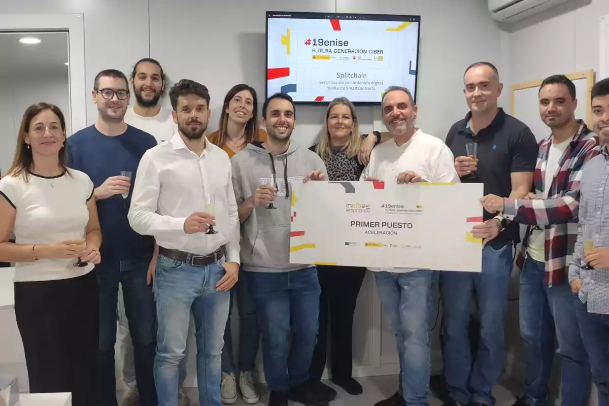 Un grupo de personas sonríe y celebra con copas en la mano mientras sostienen un cartel grande que indica que han ganado el primer puesto en un concurso de aceleración, al fondo hay una pantalla con información del evento.