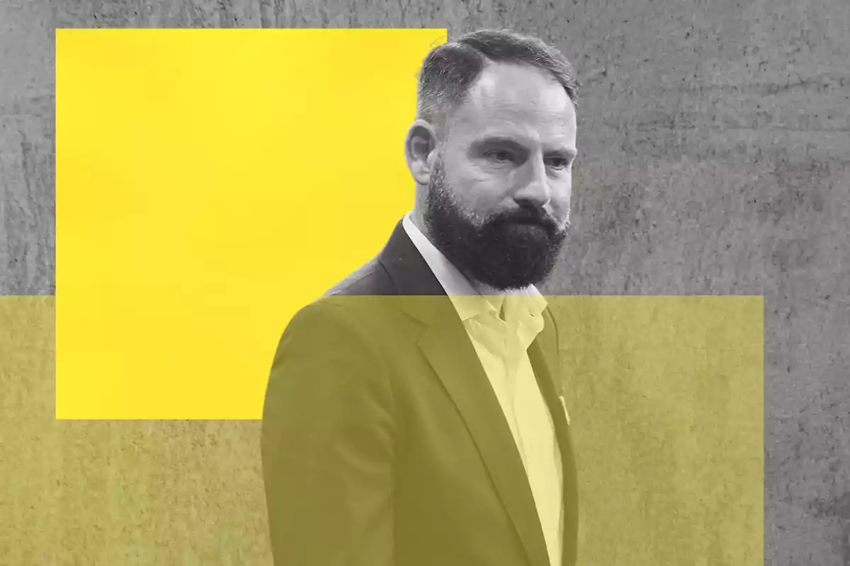 Hombre de barba y traje oscuro sobre fondo gris con figuras geométricas amarillas