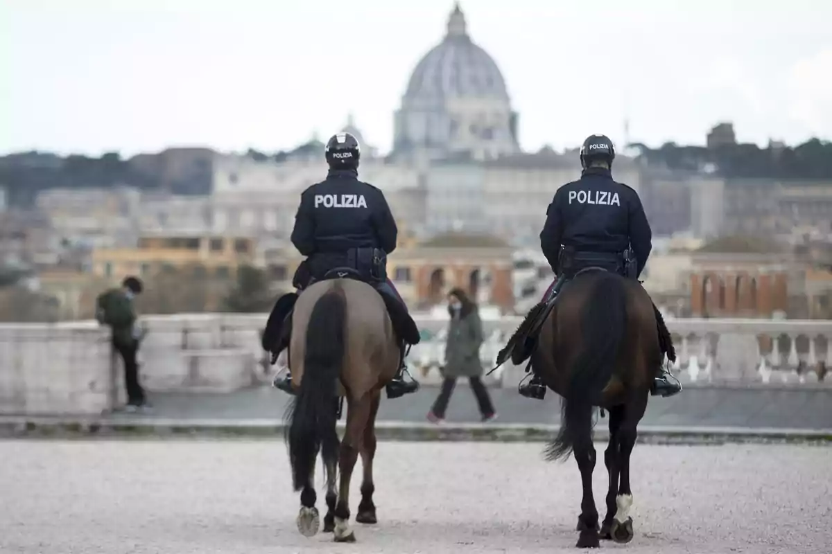 Dos policías montados patrullan una zona urbana con la cúpula de la Basílica de San Pedro al fondo Dos policías montados patrullan una zona urbana con la cúpula de la Basílica de San Pedro al fondo