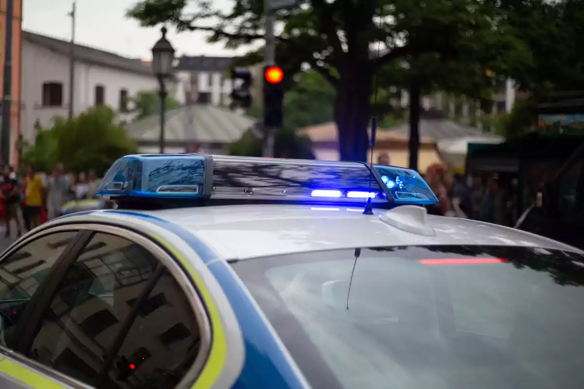 Coche de policía con luces encendidas en una calle urbana durante el día Coche de policía con luces encendidas en una calle urbana durante el día