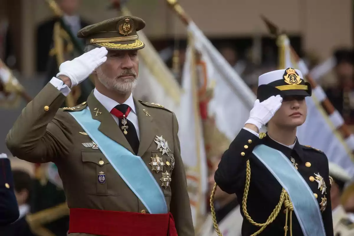 Dos personas vestidas con uniformes militares realizan un saludo durante una ceremonia oficial Dos personas vestidas con uniformes militares realizan un saludo durante una ceremonia oficial