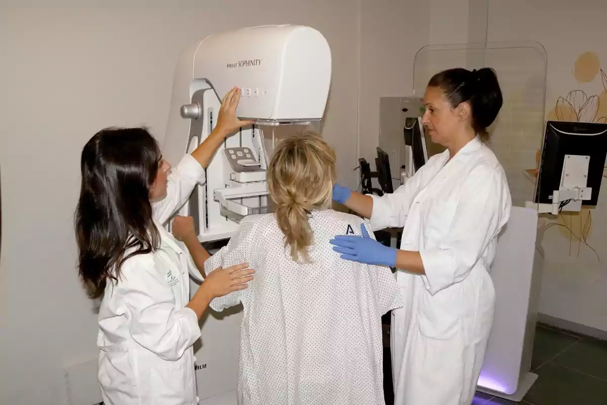 Dos profesionales de la salud asisten a una paciente durante la realización de una mamografía en una clínica