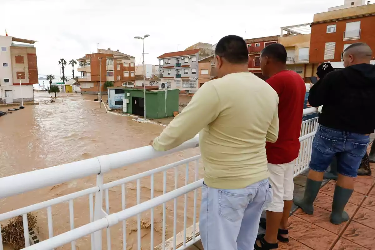 Varias personas observan desde un puente una calle inundada en una zona urbana tras una fuerte lluvia Varias personas observan desde un puente una calle inundada en una zona urbana tras una fuerte lluvia