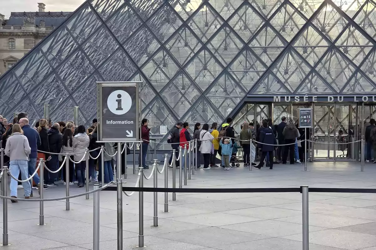 Personas haciendo fila para entrar al Museo del Louvre frente a la pirámide de cristal en París Personas haciendo fila para entrar al Museo del Louvre frente a la pirámide de cristal en París