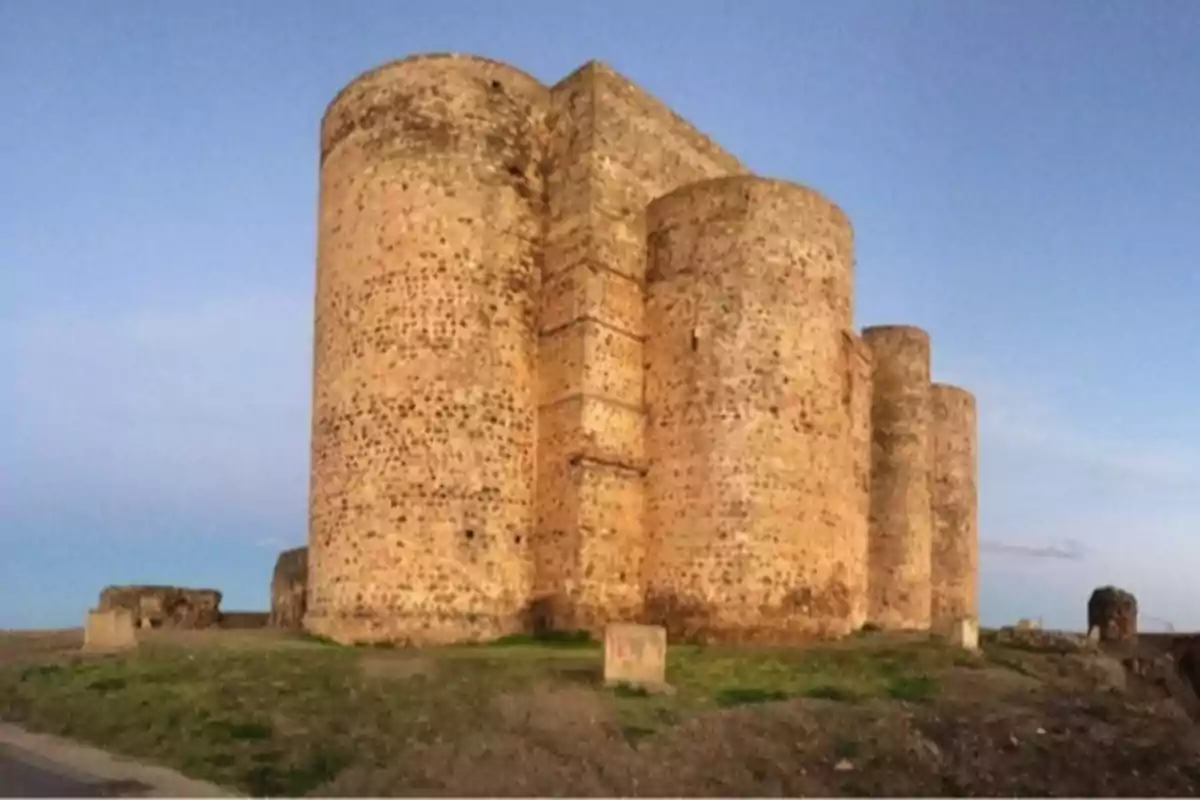 Castillo de piedra antiguo con torres redondas bajo un cielo despejado al atardecer
