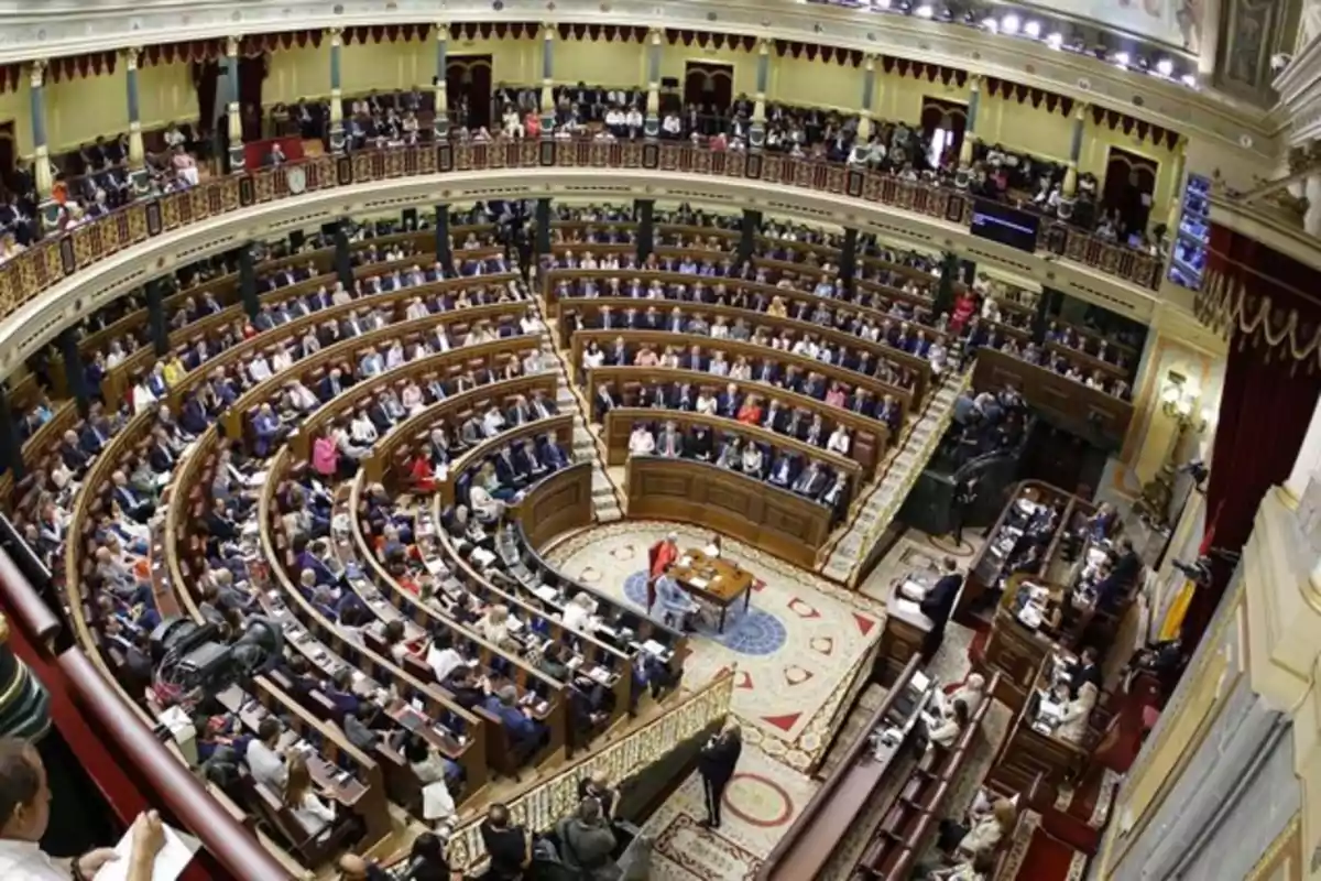 Vista panorámica del interior de un parlamento con numerosos diputados sentados en bancas semicirculares durante una sesión