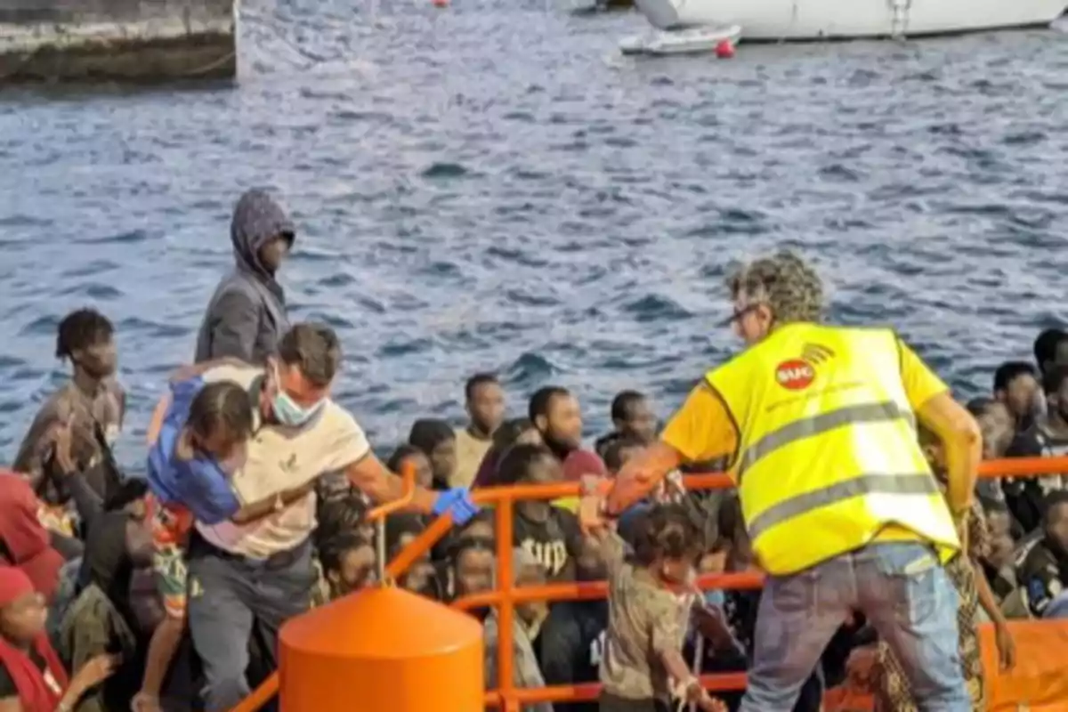 Un grupo de personas migrantes es asistido por rescatistas mientras desembarcan de una embarcación en el mar Un grupo de personas migrantes es asistido por rescatistas mientras desembarcan de una embarcación en el mar