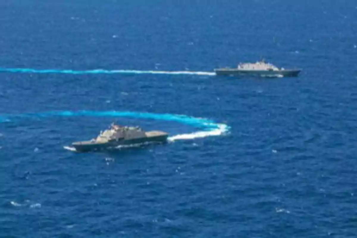 Dos barcos de guerra navegando en el mar dejando estelas en el agua