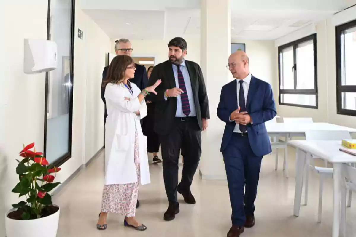 Varias personas conversan mientras recorren un pasillo luminoso en un entorno hospitalario moderno Varias personas conversan mientras recorren un pasillo luminoso en un entorno hospitalario moderno