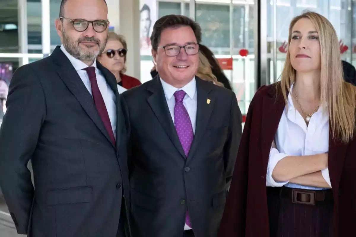 Tres personas vestidas de manera formal posan para una foto en un entorno profesional o institucional Tres personas vestidas de manera formal posan para una foto en un entorno profesional o institucional