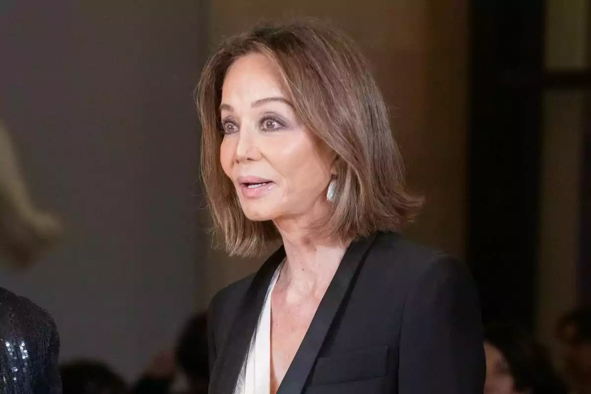 Mujer de cabello castaño corto y liso con saco negro y blusa clara en un evento formal Mujer de cabello castaño corto y liso con saco negro y blusa clara en un evento formal