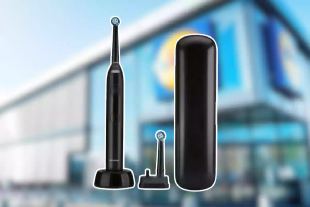Cepillo de dientes eléctrico negro con base, cabezal de repuesto y estuche frente a un edificio desenfocado