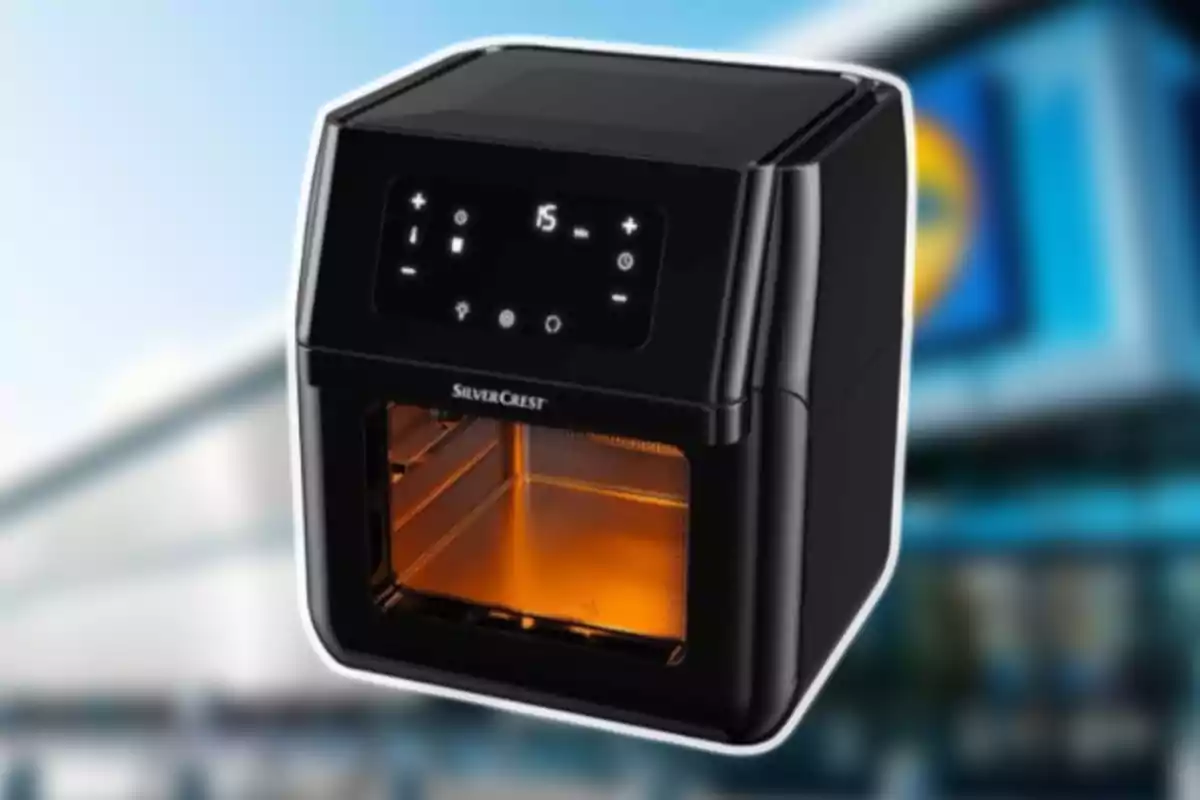 Freidora de aire negra SilverCrest con panel digital encendida sobre un fondo desenfocado