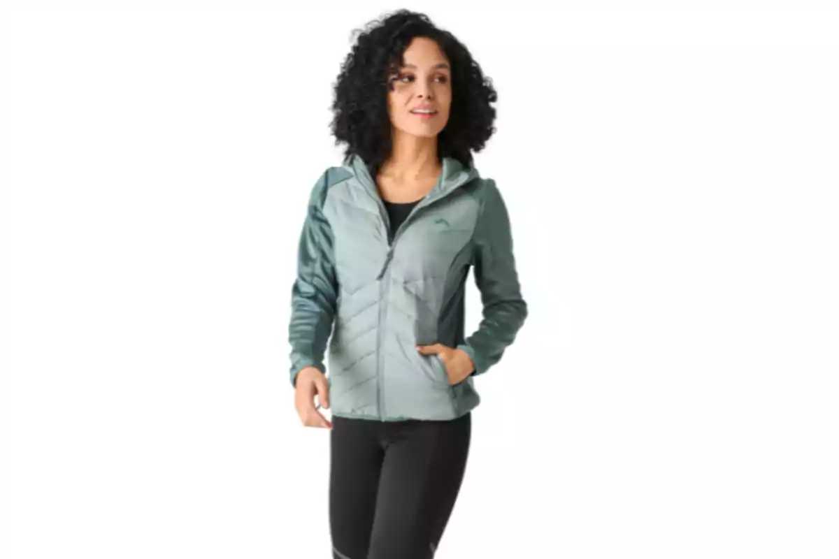 Mujer con chaqueta deportiva verde claro y pantalones negros posando sobre fondo blanco