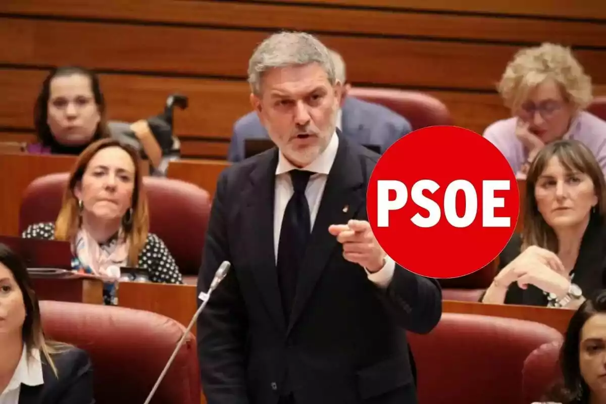 Hombre de cabello canoso y barba hablando en un parlamento rodeado de otras personas con un círculo rojo que tiene el texto PSOE